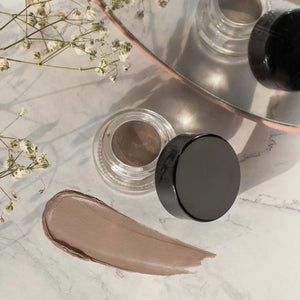 MIANIMED premium skincare product with cream and container on marble surface, accented by delicate flowers and a reflective mirror.