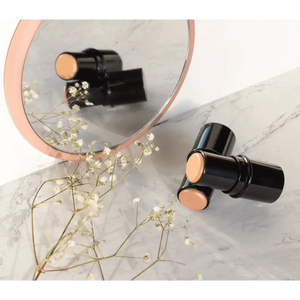 MIANIMED premium skincare sticks and flowers reflected in a round mirror on marble surface
