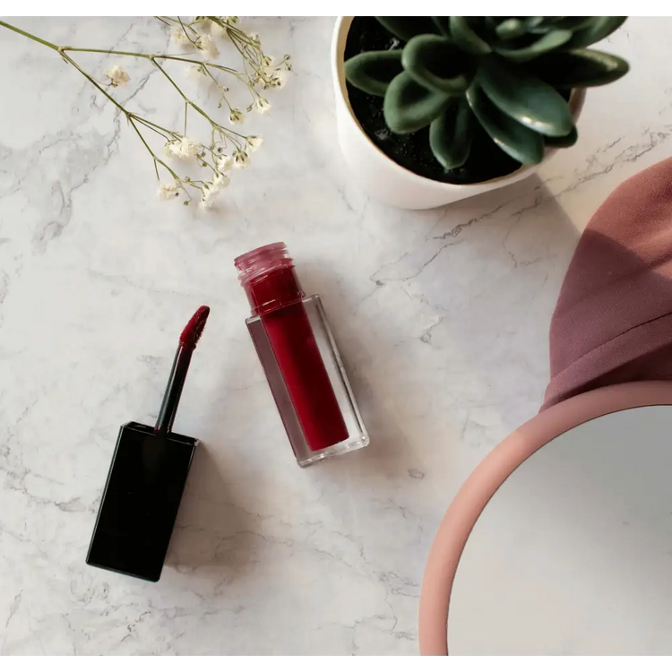 "Premium MIANIMED red liquid lipstick with succulent plant and mirror on marble surface - skincare essentials display"